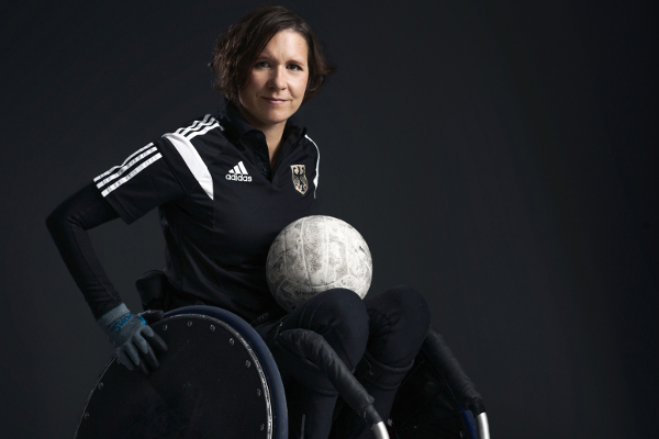 Britta Kripke in ihrem Rugby-Rollstuhl mit einem Rugby-Ball auf dem Schoß.