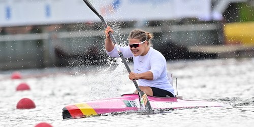Felicia Laberer in ihrem Kanu mit Sonnenbrille und einem angestrengten Gesichtsausdruck. Seitlich spritz das Wasser vom austretenden Paddel. 