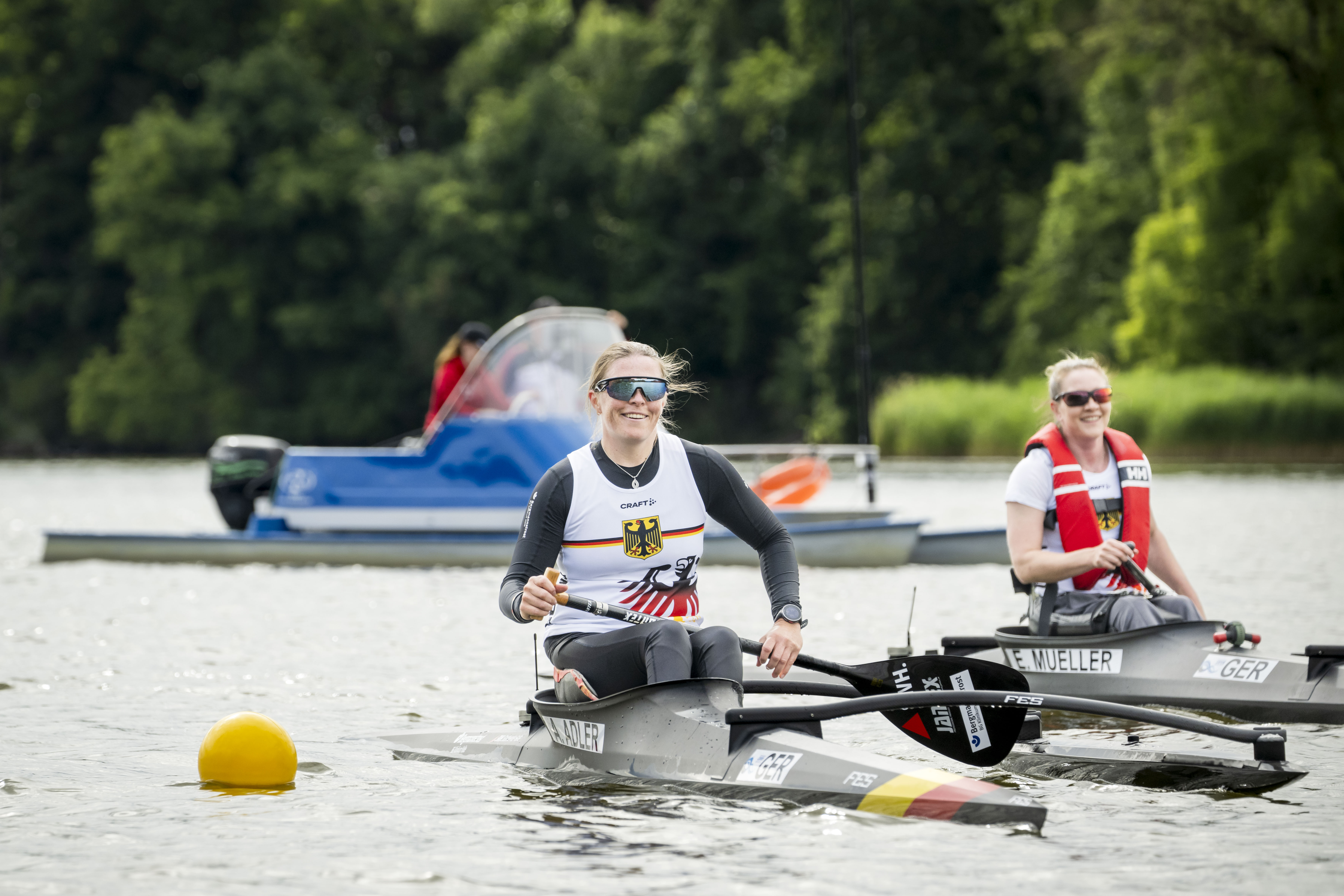 Anja und Edina in ihren Booten auf dem Wasser. Beide tragen sonnenbrillen und lächeln.